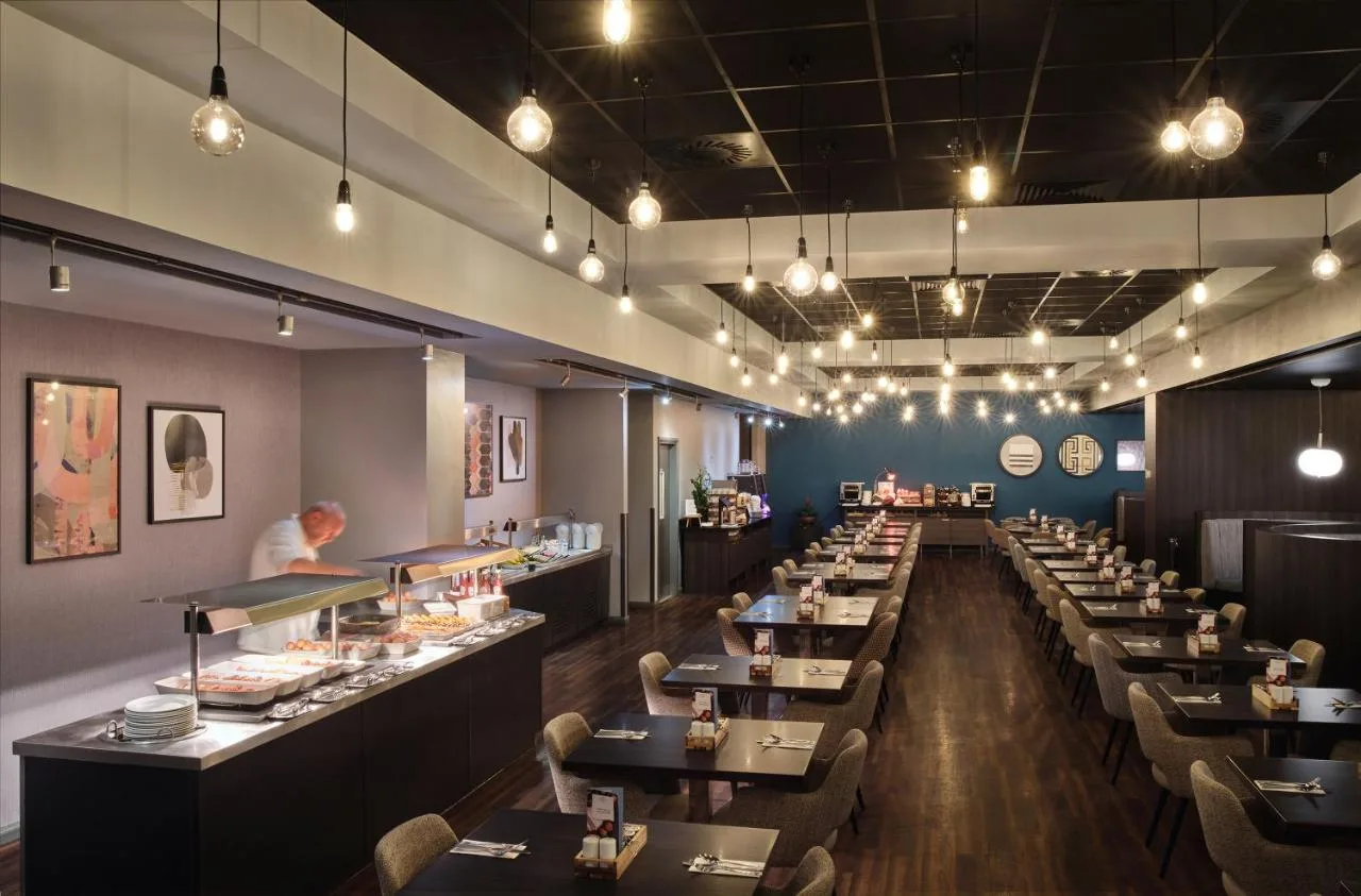 a restaurant with long tables and a chef preparing food at Crowne Plaza Birmingham City by IHG in Birmingham