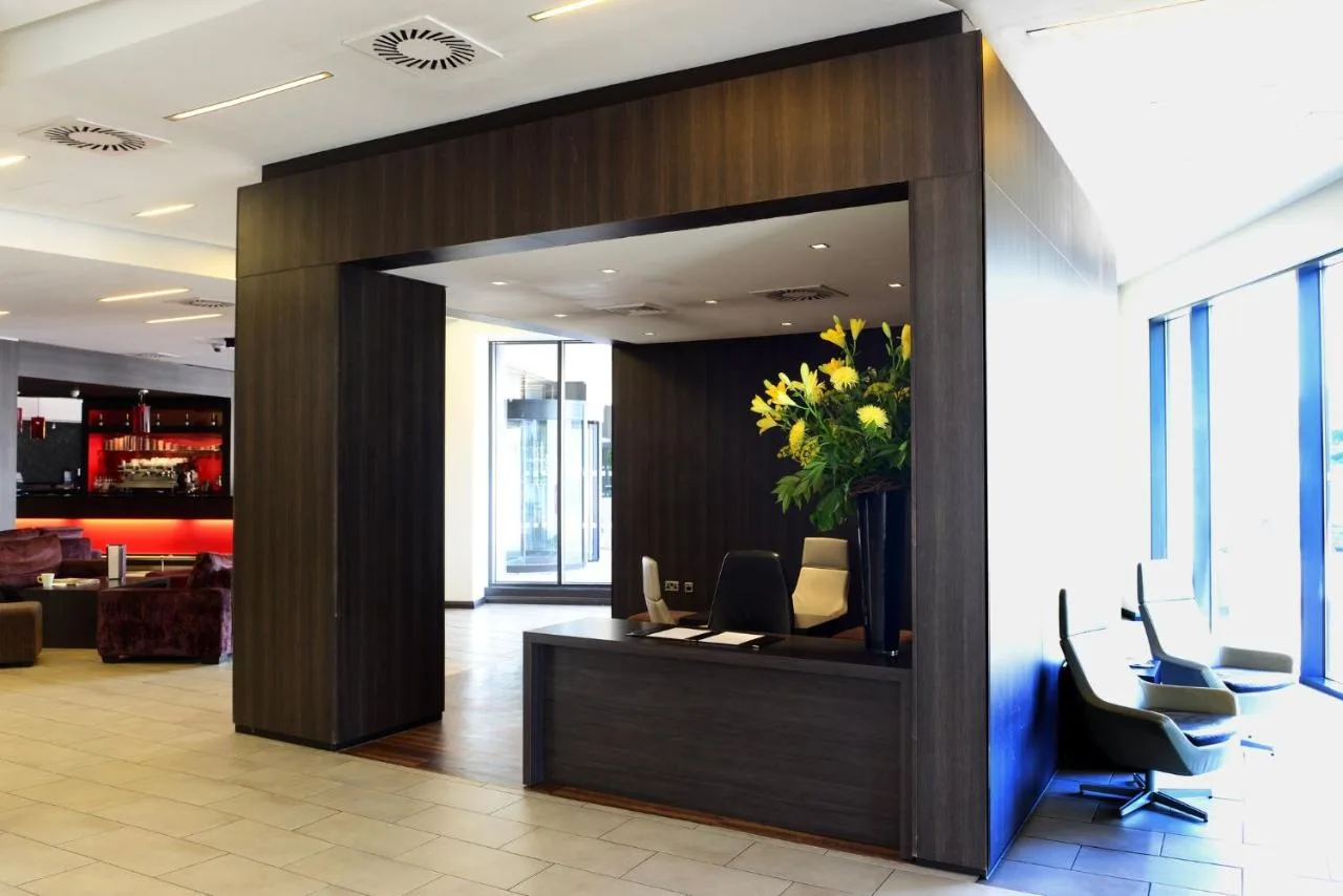 an office lobby with a reception desk with a plant at Crowne Plaza Birmingham City by IHG in Birmingham